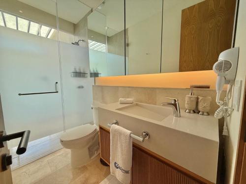Un baño con lavabo, inodoro y espejo. en Zantamar, Penthouse 605B, en Cruz de Huanacaxtle
