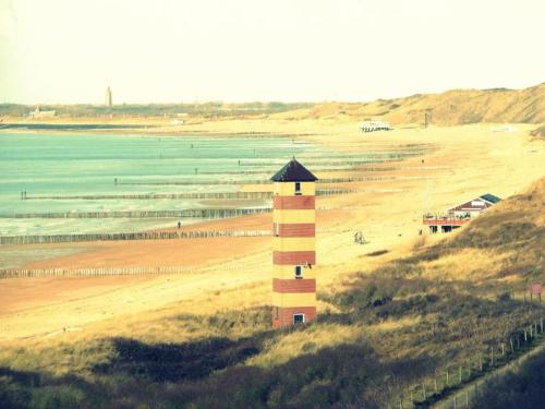 a lighthouse on a beach next to the ocean at Apartment in Koudekerke near Sandy Beach in Koudekerke
