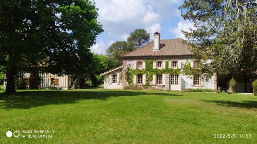 une vieille maison avec une grande cour gazonnée dans l'établissement Maison de maître, à Sabres