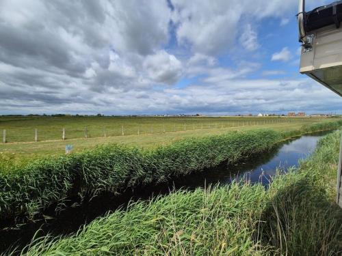 a river in a field next to a fence at Whitstable 3 Bedroom Home in Seasalter