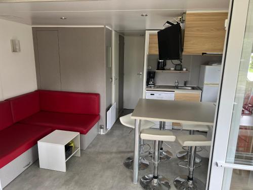 Cette petite chambre comprend un canapé rouge et une table. dans l'établissement La Grande Métairie Location Mobil-Home 4p, à Carnac