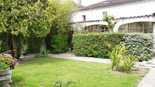 un jardin en face d'une maison blanche dans l'établissement Gîte du Corupsis, à Villeneuve-sur-Lot