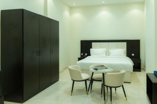a bedroom with a bed and a table and chairs at شقق أون يسن للشقق المخدومة On Yassen Apartments Serviced in Unayzah