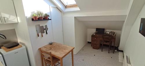 une chambre mansardée avec une table, un bureau et une fenêtre dans l'établissement Studio of 20 m2 near the Catacombes de Paris, à Paris