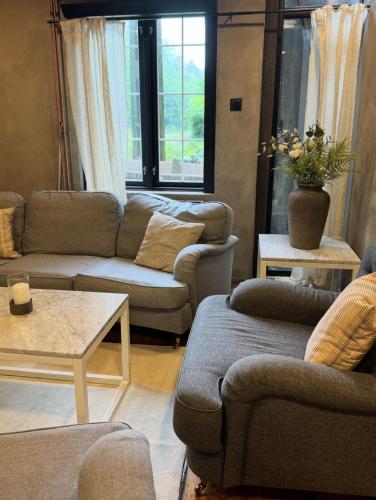 a living room with two couches and a table at Tree Top Hill - The Old Station House - Båstad Holiday Apartments in Båstad