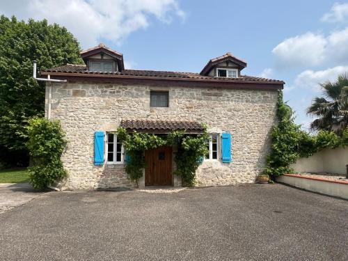 une maison en pierre avec des volets bleus et une porte dans l'établissement Maison sur Lot, à Villeneuve-sur-Lot