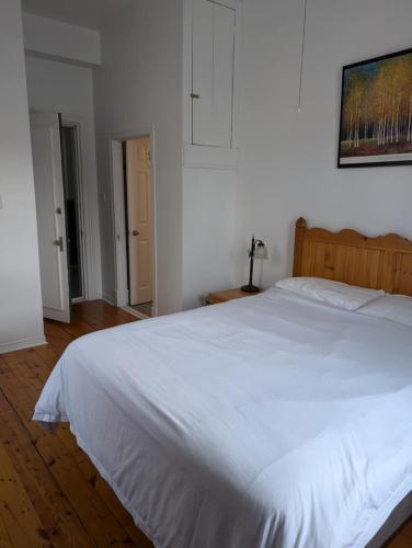 a large white bed in a bedroom with a wooden floor at Aux petits oiseaux in Baie-Saint-Paul