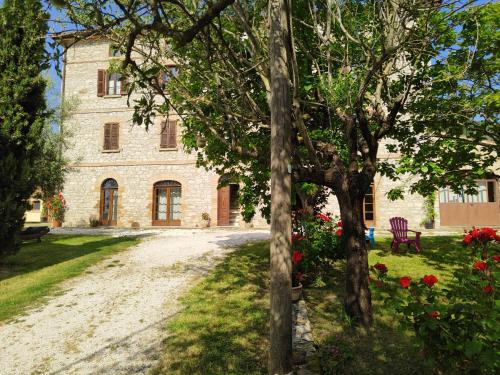 a large stone building with trees and flowers in front of it at Agriturismo Montefiorentino in Frontino