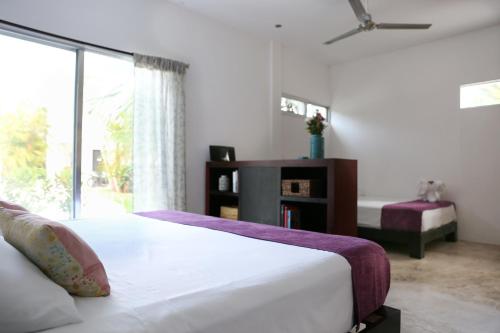 a white bedroom with a bed and a window at Villas H2O in Tulum