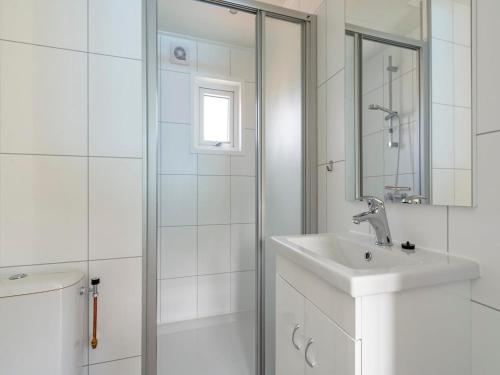 Un baño blanco con lavabo y ducha. en Chalet on Texel near Beach and Forest, en De Koog