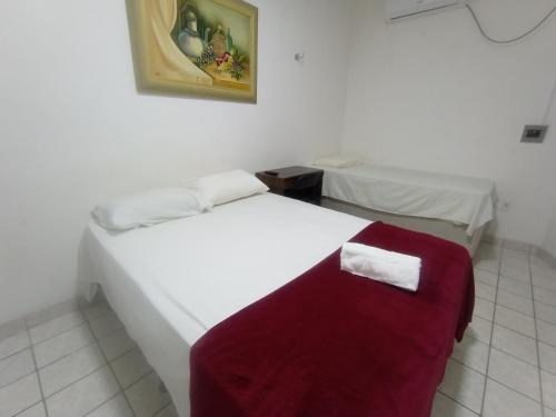 a bedroom with two beds and a red bench at Pousada Maria Bonita - Centro, 10min da Praia de Camapum, Macau RN in Macau