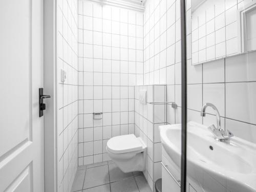 a white bathroom with a toilet and a sink at Holiday Home in Texel near the Beach in De Koog