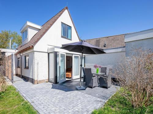 a patio with a table and an umbrella at Holiday Home in Texel near the Beach in De Koog