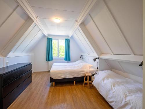 a attic bedroom with two beds and a window at Holiday Home in Texel near the Beach in De Koog