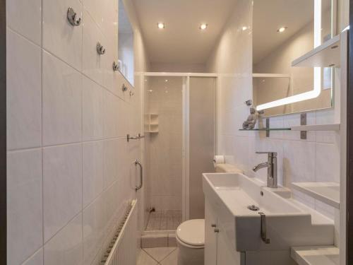 a white bathroom with a sink and a toilet at Bungalow near Sint Maartenszee Beach in Sint Maartensvlotbrug