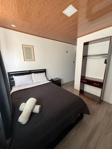 a bedroom with a black bed with two towels on it at Bunker593 Inn in Tena