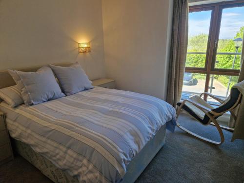 a bedroom with a bed and a chair and a window at Westport luxury apartment Knockranny in Westport
