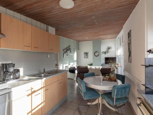 a kitchen with a table and blue chairs in a room at Holiday Home Sint Maartenszee near Beach in Sint Maartenszee