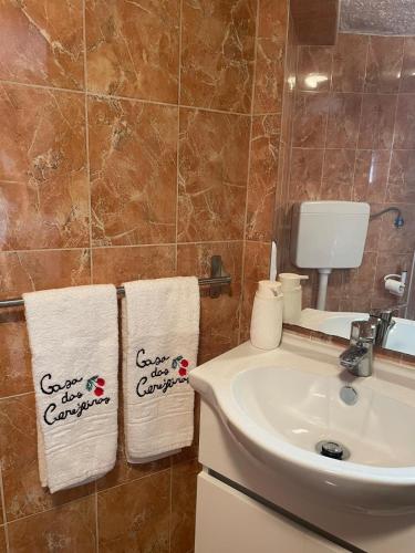 a bathroom with two towels on a sink at Casa das Cerejeiras in Pomares