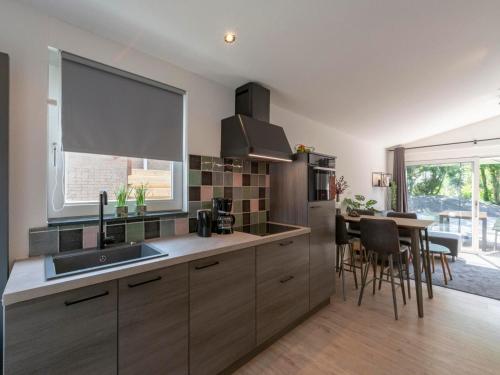 a kitchen with a sink and a table with chairs at Bungalow in Callantsoog near the Beach in Callantsoog