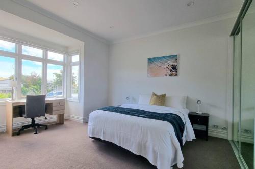 a bedroom with a bed and a desk with a computer at Spacious Remuera Bungalow with Parking and Aircon in Auckland
