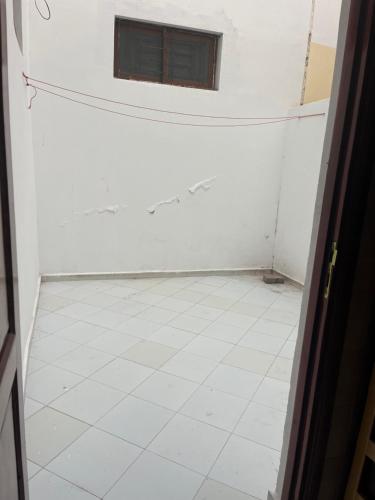 a room with a white tiled floor and a window at Rihane housse in Essaouira
