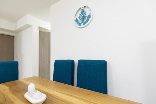 a table with blue chairs and a clock on the wall at Playa Mantas CAMA QUEEN A-C 400MB in Tarcoles