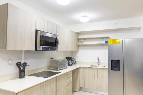 a kitchen with wooden cabinets and a stainless steel refrigerator at Playa Mantas CAMA QUEEN A-C 400MB in Tarcoles