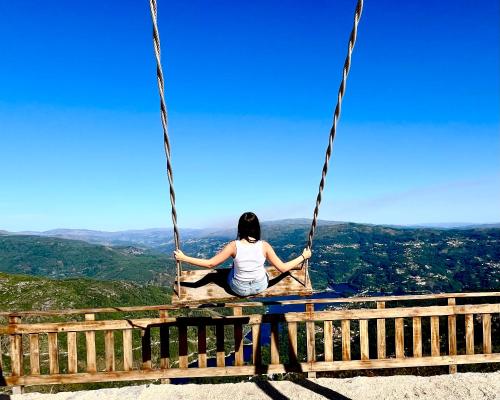 a woman sitting on a swing on top of a mountain at Casa da Fonte, Monte in Terras de Bouro