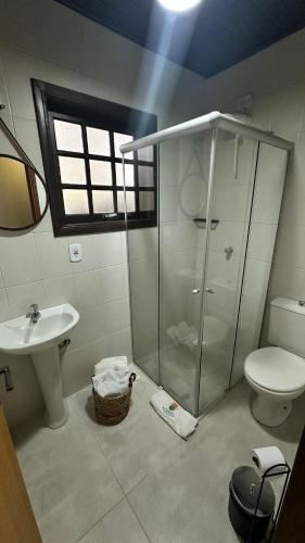 a bathroom with a shower and a toilet and a sink at Pousada Canto da Nascente in Monte Verde