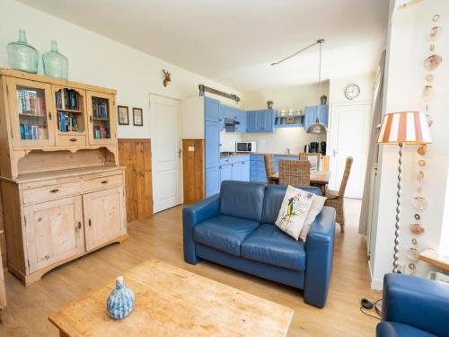 a living room with a blue couch and a kitchen at Apartment in De Koog near Texel Beach in De Koog