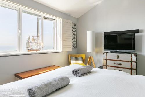 a bedroom with a white bed with a tv on the wall at Seafront townhouse in Sandgate in Sandgate