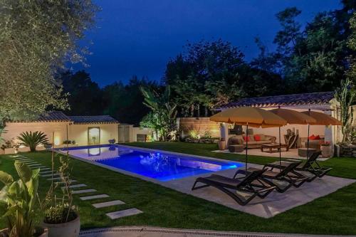 une cour avec une piscine entourée de chaises et d'un parasol dans l'établissement Dolce Apartment 3 Bedrooms 5 Guests 10min to Cannes, à Mandelieu-la-Napoule