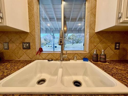 Un fregadero blanco en una cocina con ventana. en Romantic Secluded Hot Tub Fire Pit, en Joshua Tree