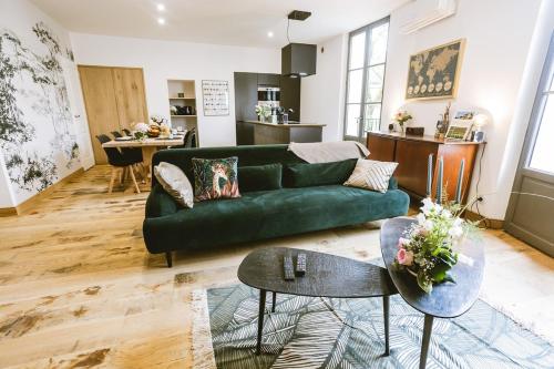 un salon avec un canapé vert et une cuisine dans l'établissement VI - Gîte des Rois de France -, à Bergerac