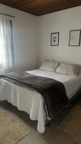 a bedroom with a large bed with white sheets at Pousada Canto da Nascente in Monte Verde