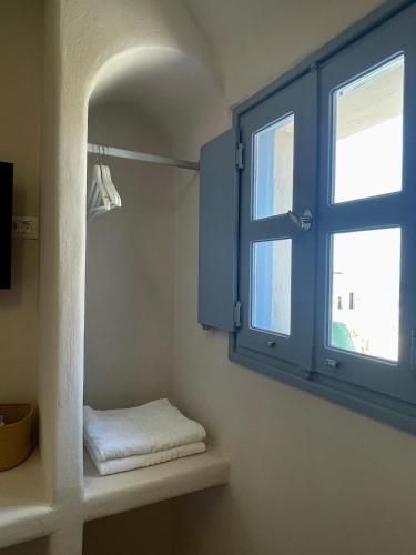 a bathroom with a window and a shelf with towels at Okeanos Suites 3, Sea & Garden View in Foinikiá