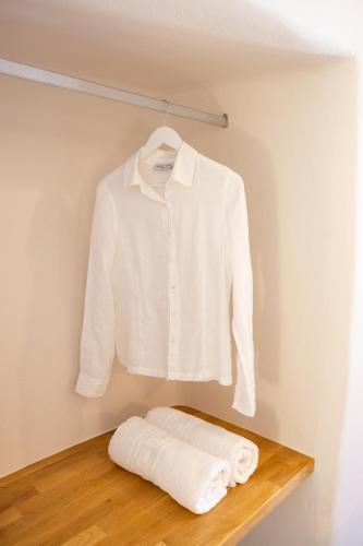 a white shirt hanging on a shelf with towels at Okeanos Suites 3, Sea & Garden View in Foinikiá