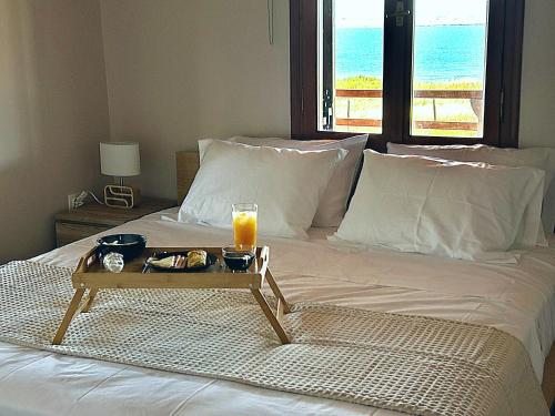 a tray of food and a glass of orange juice on a bed at Anatèlia Beach House in Portianón