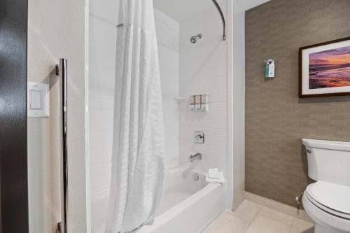 a bathroom with a tub and a toilet and a shower at La Quinta Inn & Suites by Wyndham La Habra in La Habra
