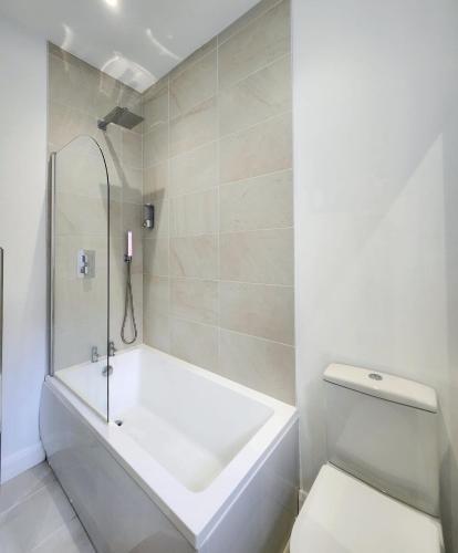 a white bathroom with a tub and a toilet at Cozy & Bright 2BR in Long Eaton in Long Eaton