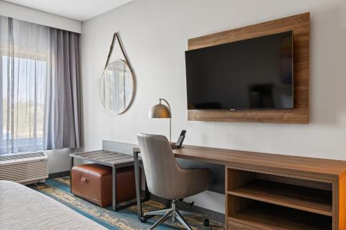 a hotel room with a desk and a television at La Quinta Inn & Suites by Wyndham La Habra in La Habra
