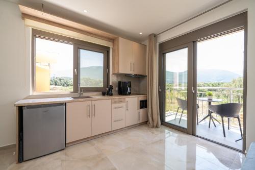 a kitchen with white cabinets and large windows and a table at Maera Apartments in Sami
