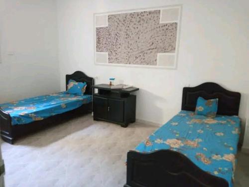Una habitación con dos camas y una mesa dentro. en Diar ghaith, en Hanshīr Qaşr Ghallāb