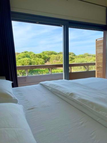 une chambre avec un lit blanc et une grande fenêtre dans l'établissement Apartments PETIT DOMAIN DE SPERONE, à Bonifacio