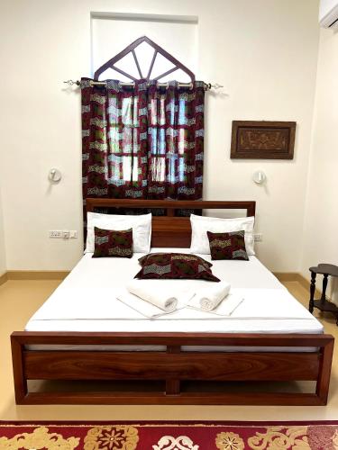 a bedroom with a large bed with white sheets and pillows at Treasures of Zanzibar House in Zanzibar City