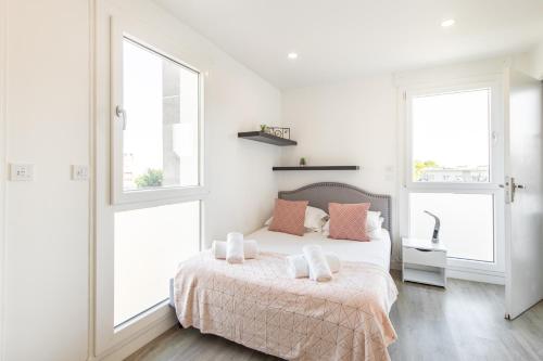 a white bedroom with a bed and two windows at Large 4 Bedroom Apartment near metro - only 30 minutes to Paris and Disneyland in Créteil