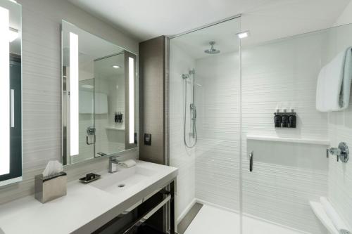 a white bathroom with a shower and a sink at AC Hotel by Marriott Boston Cleveland Circle in Boston