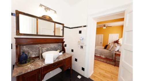 a bathroom with a sink and a mirror on a wall at William F Cody - Historic Hotel in Cimarron