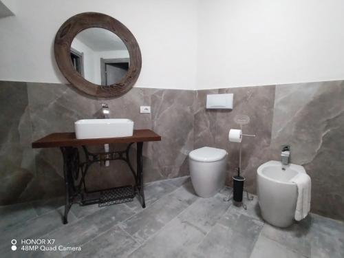 a bathroom with a sink and a toilet and a mirror at Il Loft nel Borgo in Ameglia